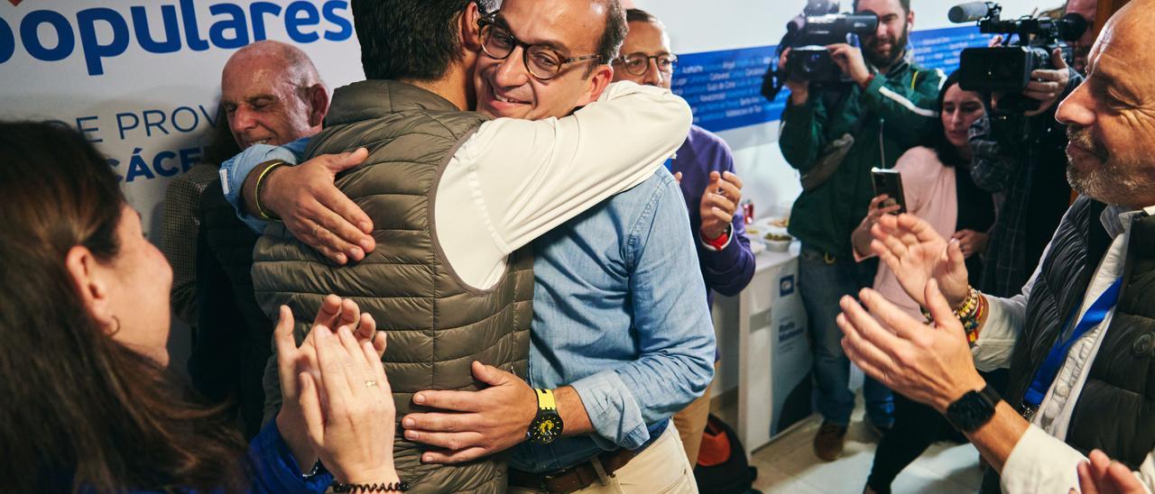 Rafa Mateos, en la sede del PP de Cáceres, abraza a su compañero Víctor Bazo en presencia de Pedro Muriel.