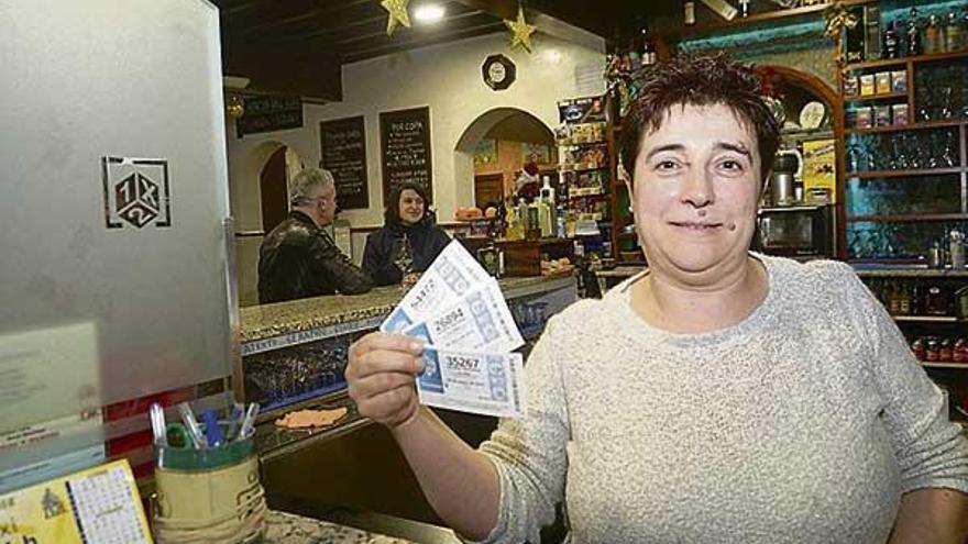 La trabajadora de un despacho de lotería muestra décimos del sorteo del Niño.  // Noé Parga