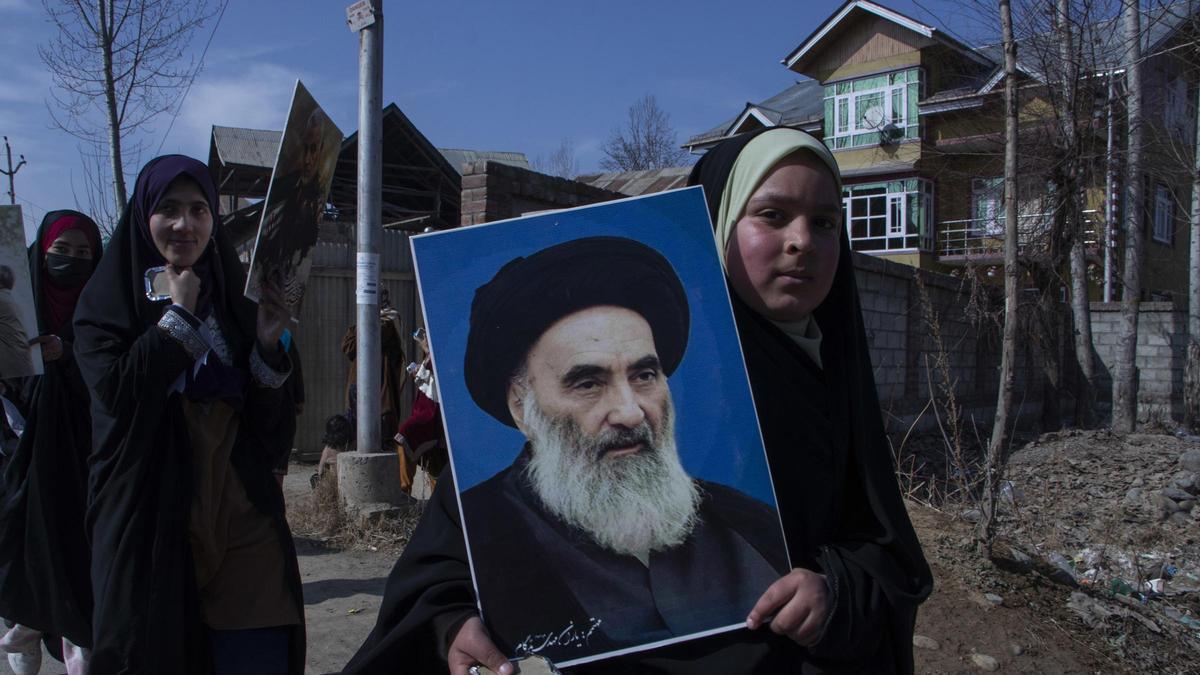 Imagen de una adolescente con un retrato del ayatolá Alí Sistani, la máxima autoridad religiosa chií en Irak.
