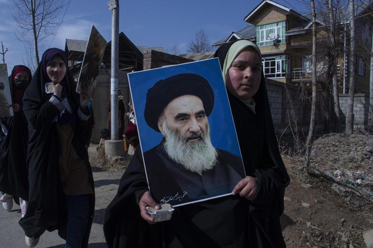 Imagen de una adolescente con un retrato del ayatolá Alí Sistani, la máxima autoridad religiosa chií en Irak.