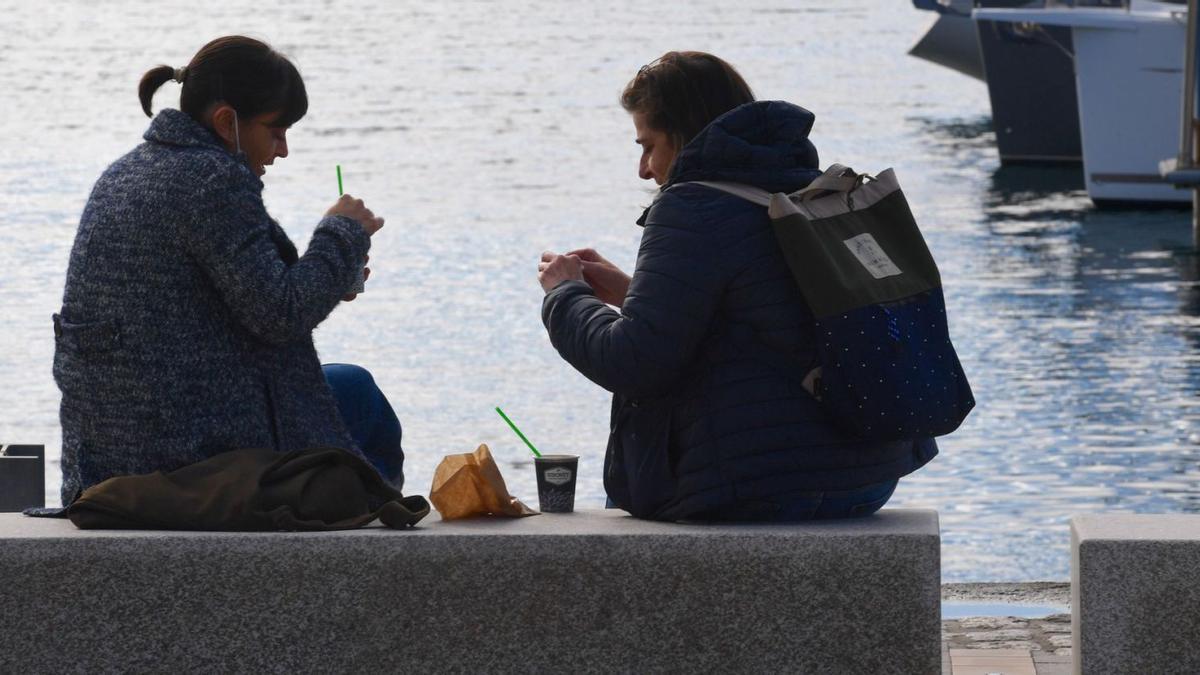 Dos jóvenes se toman un café en los muelles de A Coruña, cuya provincia ha aumentado población. |   // CARLOS PARDELLAS