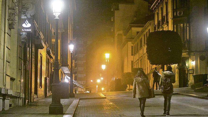 La calle Carreño Miranda, ayer de noche, con la nueva iluminación con bombillas led en primer término y la antigua, en tono anaranjado, al fondo.