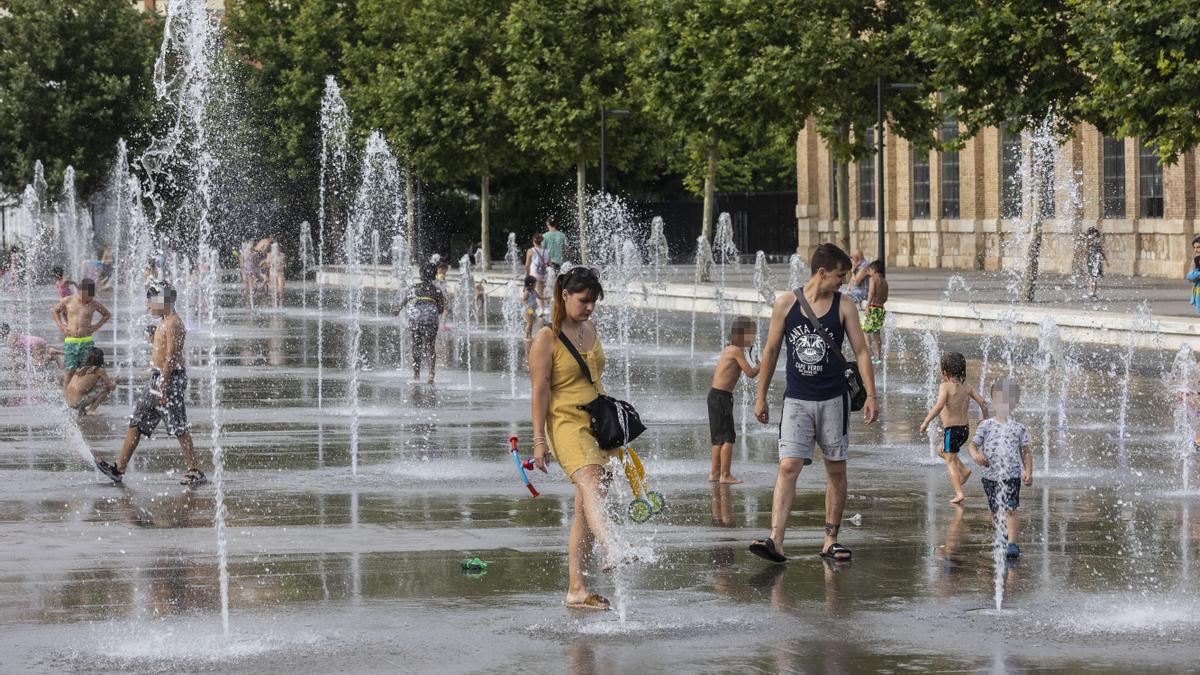 varias personas se refrescan en la fuente del Parc Central de València.