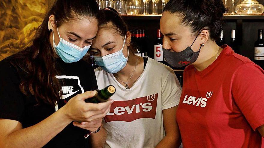 Marta Piquero, Sara Roces y Natasha Lee observan la etiqueta conmemorativa.