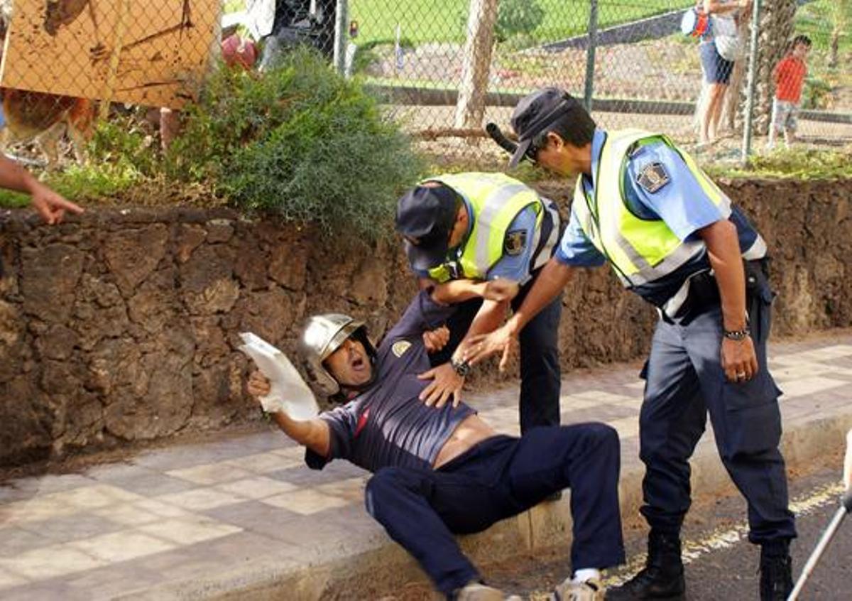 Dos agentes agarran a uno de los bomberos que trataba de mostrarles el permiso de la manifestación. i  TEMRO