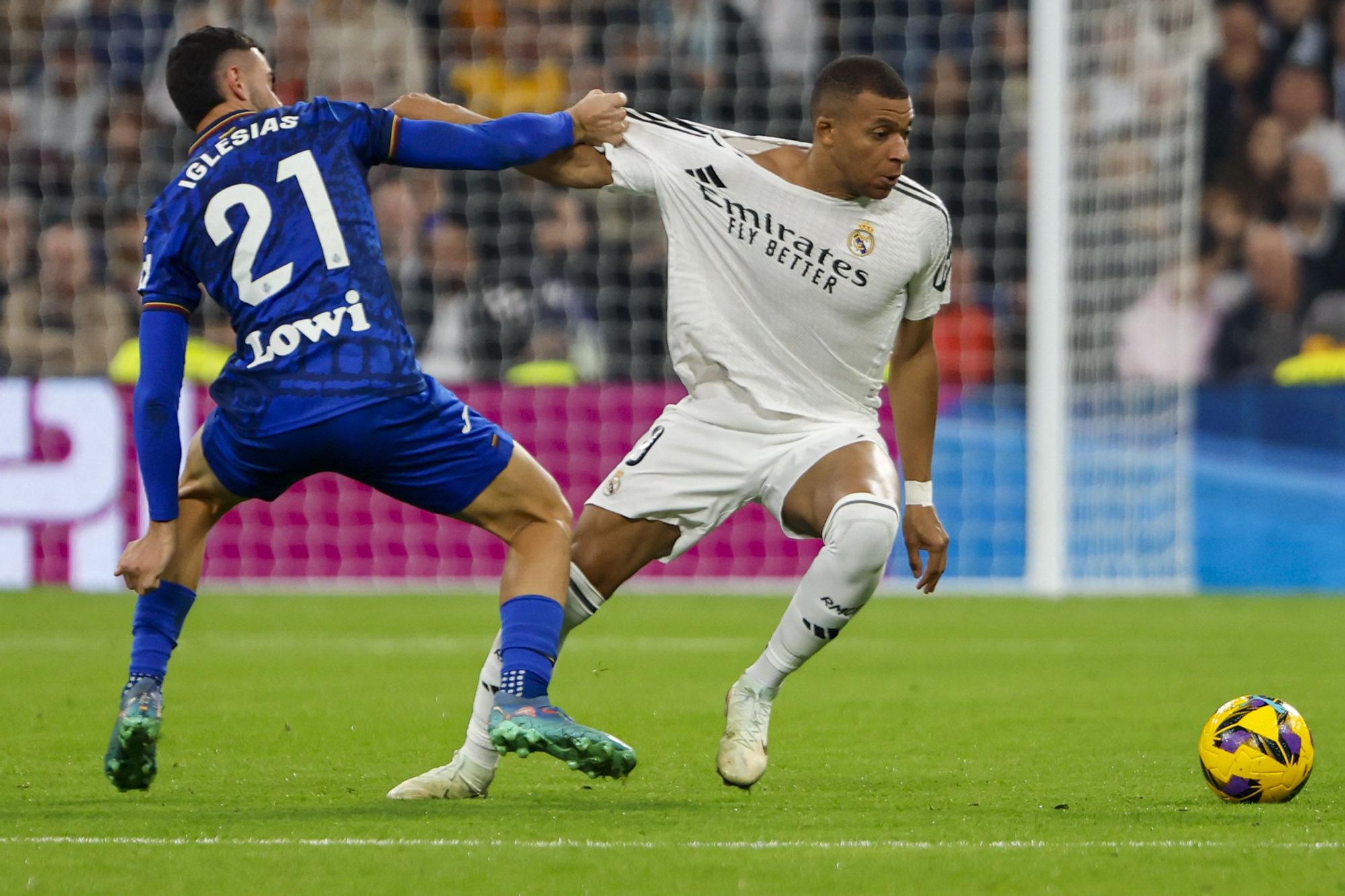 El delantero francés del Real Madrid Kylian Mbappé (d) pelea un balón con el defensa del Getafe Juan Iglesias en el partido de LaLiga entre el Real Madrid y el Getafe, este domingo en el estadio Santiago Bernabéu. EFE/ Sergio Pérez. (Real Madrid)