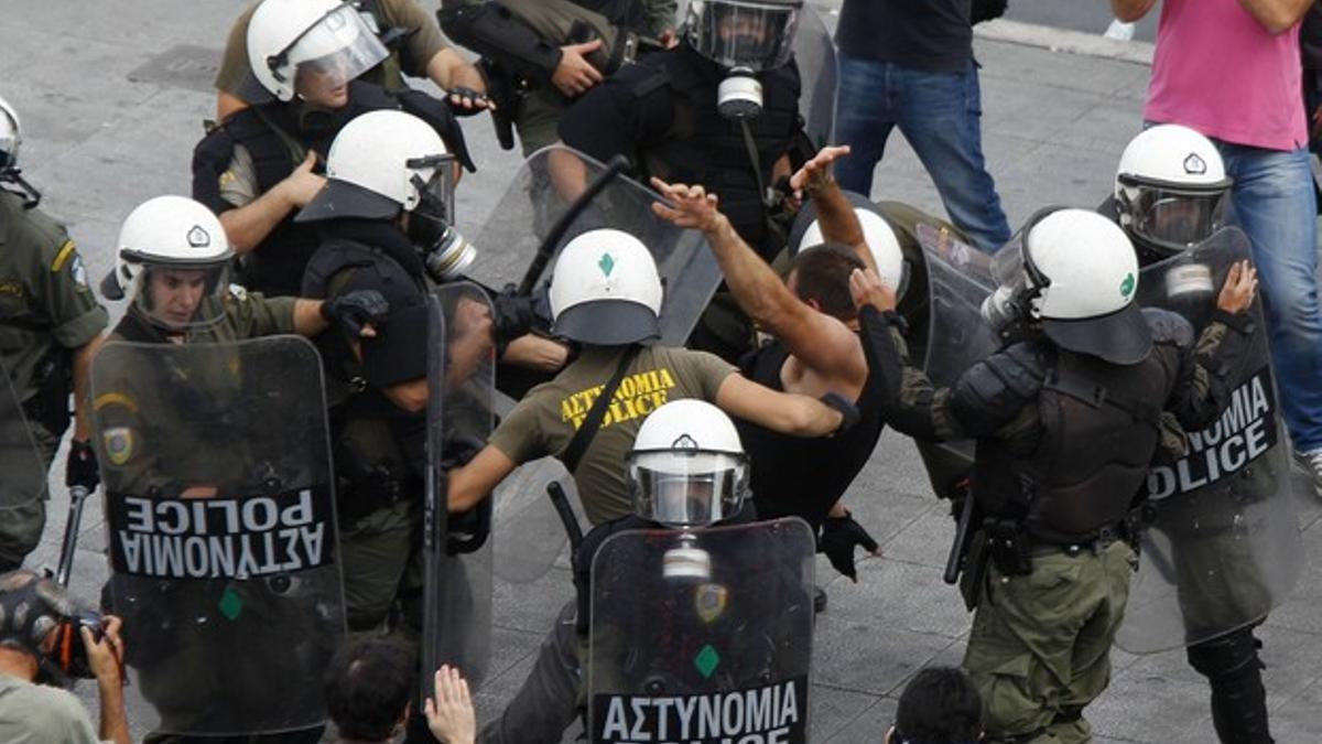 Policías golpean a un manifestante durante la manifestación de Atenas.