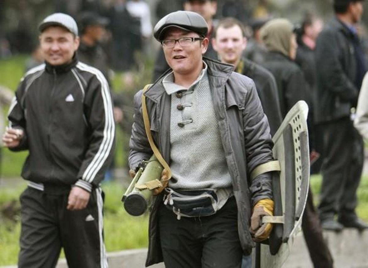 A protester carries a RPG and a riot shield during clashes with riot police in Bixkek
