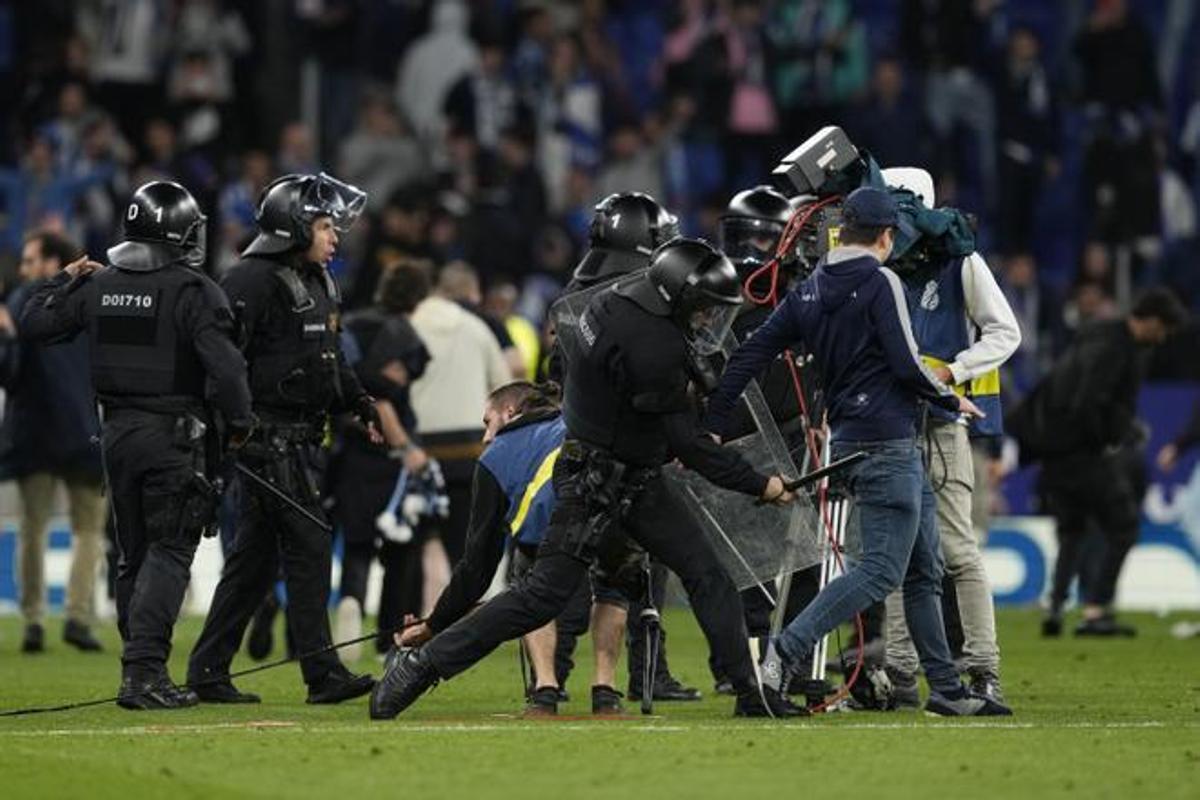 Un mosso golpea a un aficionado del Espanyol que invadió el campo.