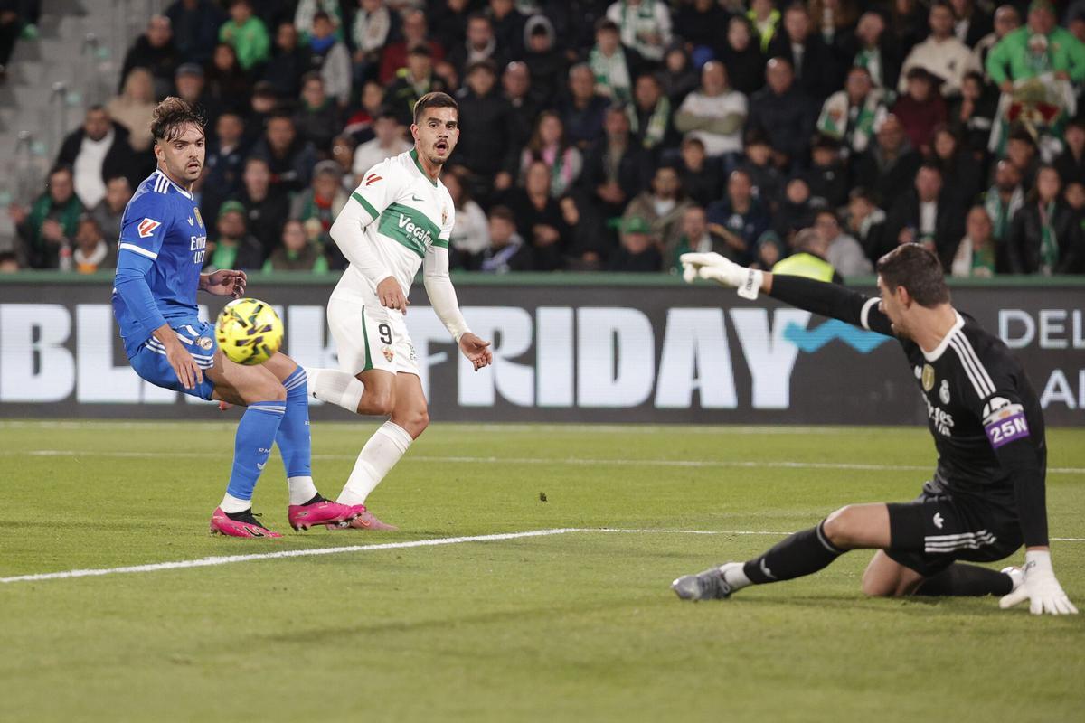 El guardameta del Real Madrid Thibaut Courtois (d) despeja un balón ante André Silva (c), del Elche, durante el partido de la jornada 13 de LaLiga entre el Elche CF y el Real Madrid, este domingo en el estadio Martínez Valero. EFE/Manuel Bruque. (Elche) (Real Madrid)