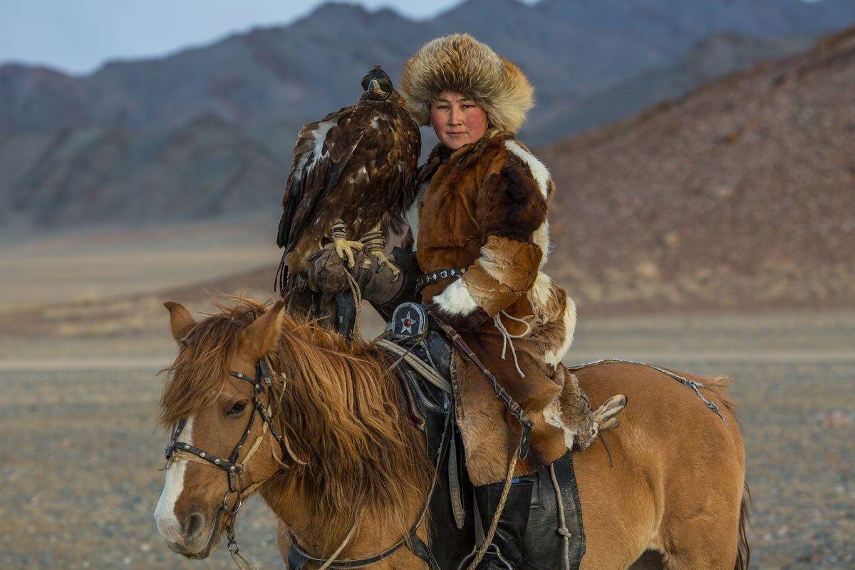 Mujer a caballo y con su águila en las áridas tierras del desierto de Mongolia