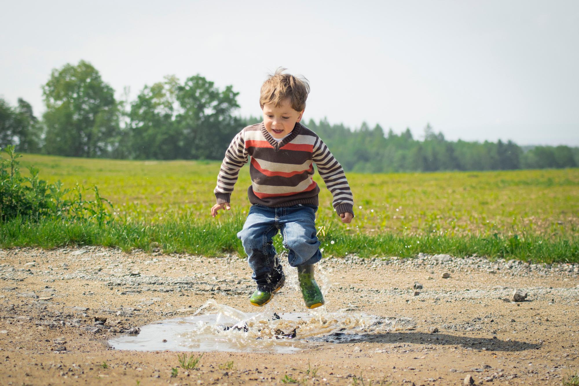 Un niño juega saltando en un charco