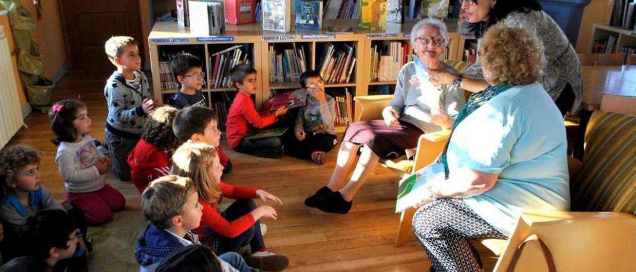 Adela de la Fuente, Ana Méndez y María Jesús Álvarez leen uno de los cuentos a los pequeños, ayer en la biblioteca de Coaña.