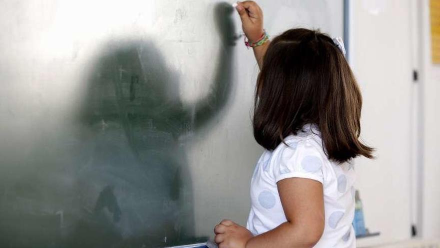 Una niña escribe en la pizarra de su clase.