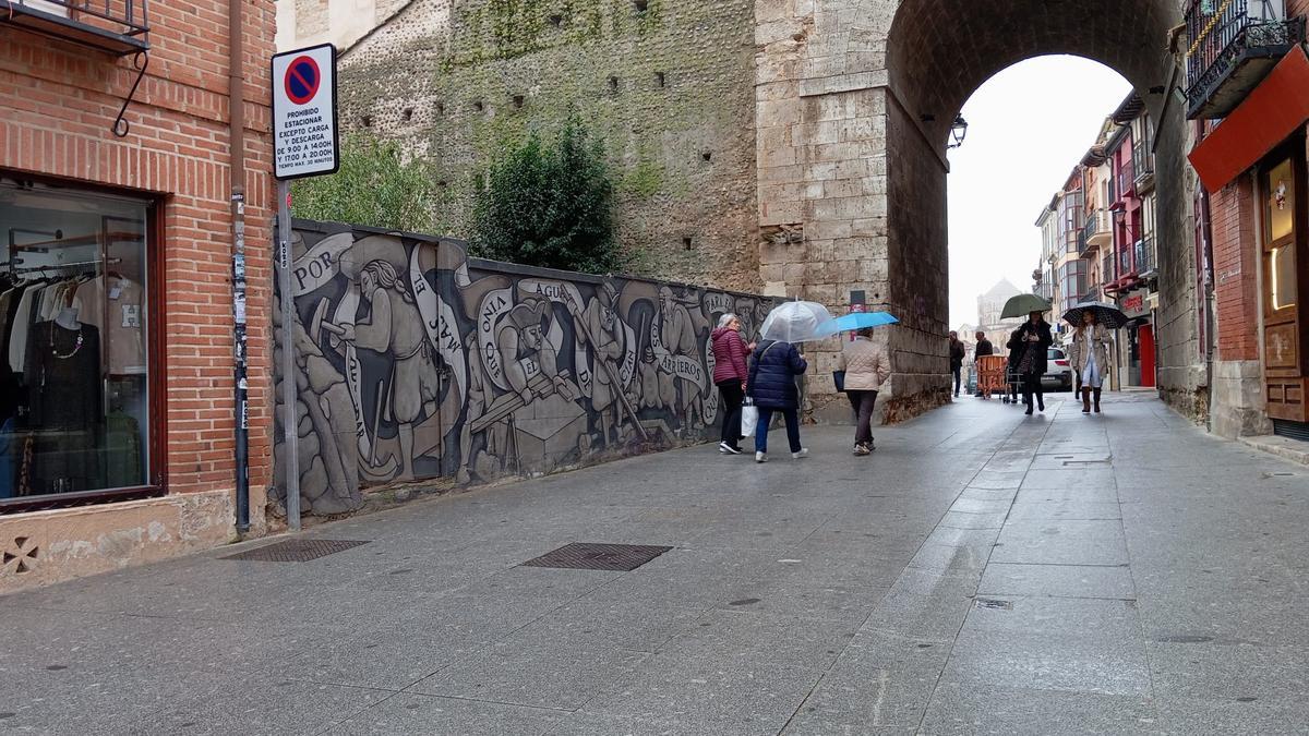 Ciudadanos pasean por el mural de la construcción del Arco del Reloj.