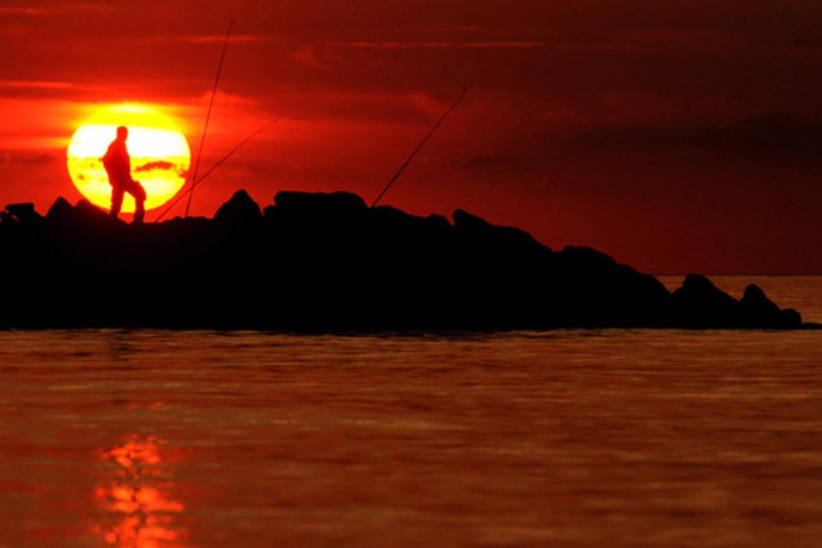 Un pescador observa la posta de sol al Mar Bàltic, a Schönberg (Alemanya)
