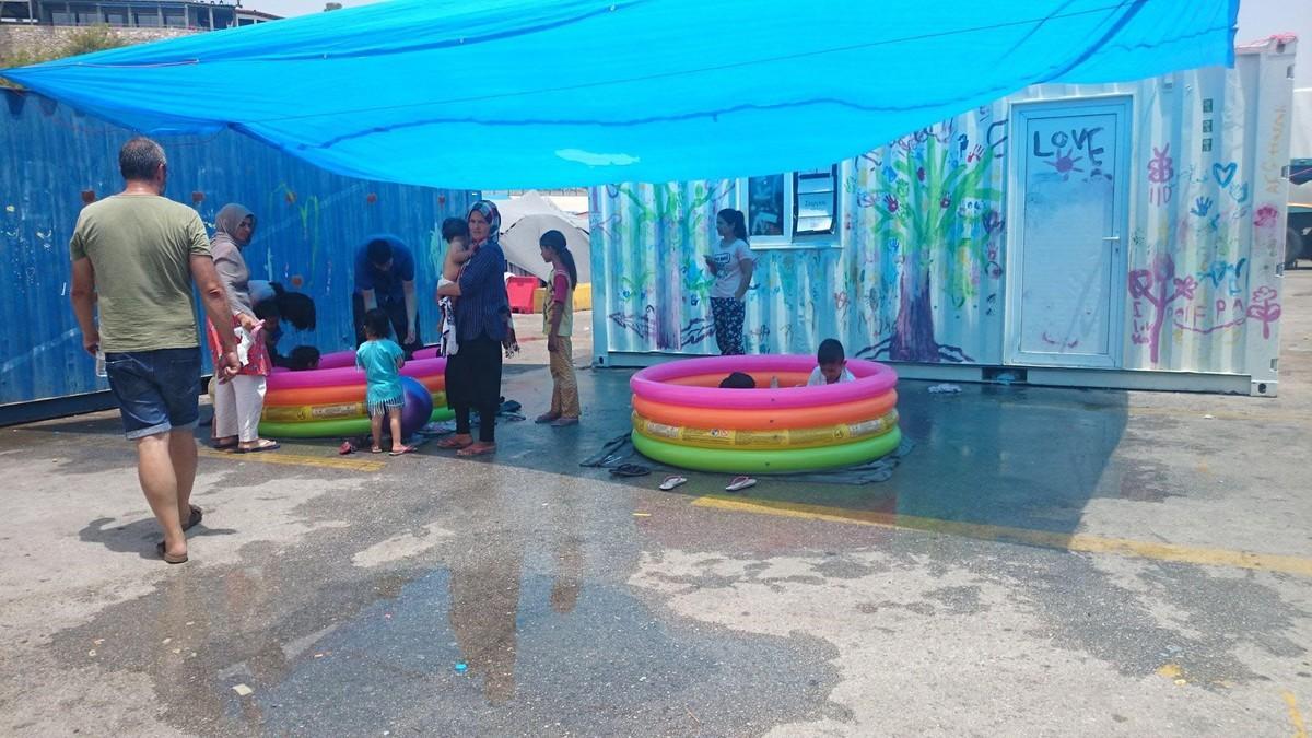 Niños refrescándose en piscinas de plástico, en el campo de refugiados de El Pireo.