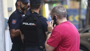 Un hombre habla por teléfono junto a tres policías, en Madrid.