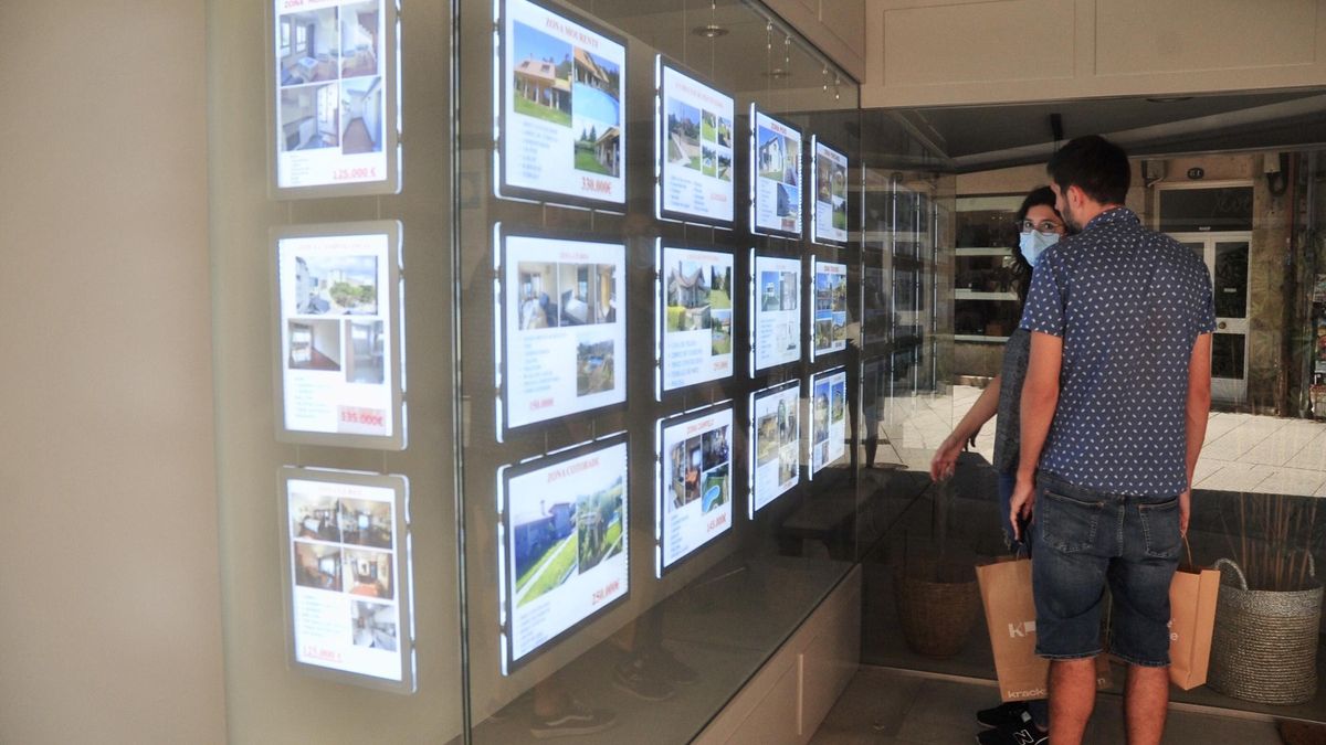Dos jóvenes observan el escaparate de una inmobiliaria en Pontevedra