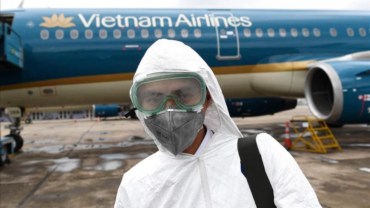 Un trabajador equipado con máscara para evitar el contagio por coronavirus se dispone a desinfectar un avión de Vietnam Airlines
