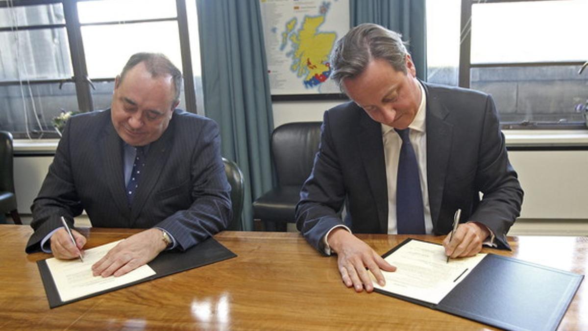 El primer ministro británico, David Cameron (derecha), y el nacionalista Alex Salmond firman el acuerdo sobre el referendo de independencia escocesa.