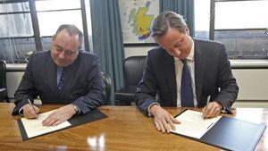 El primer ministro británico, David Cameron (derecha), y el nacionalista Alex Salmond firman el acuerdo sobre el referendo de independencia escocesa.