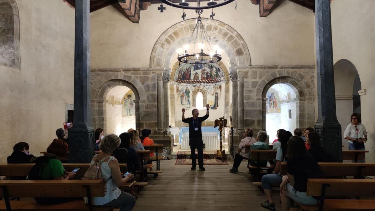 Los visitantes atienden a las explicaciones del guía sobre en la iglesia de San Vicente de Serrapio.