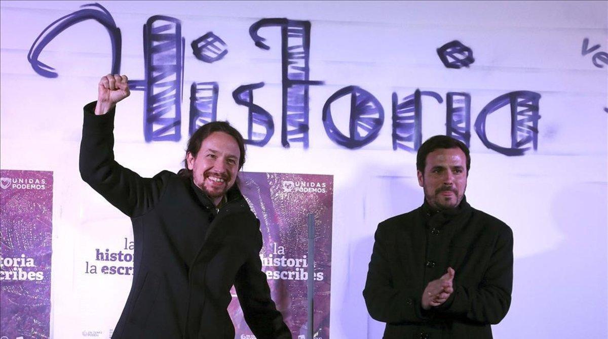 El secretario general de Podemos, Pablo Iglesias, y el líder de IU, Alberto Garzón, en la pegada de carteles en el distrito madrileño de Usera.