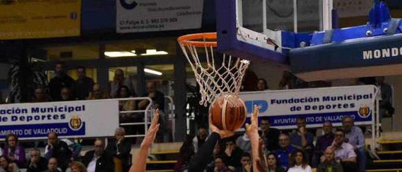 Douvier lanza a canasta ante la oposición de dos jugadores del Carramimbre y el ala-pívot del Oviedo Baloncesto Ignacio Rosa.