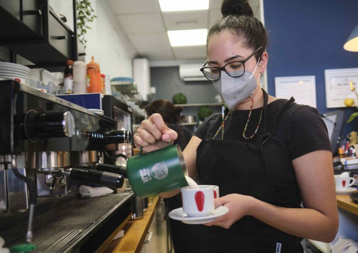 Una trabajadora autónoma prepara una bebida en su cafetería. | | C. W. LAURITSEN