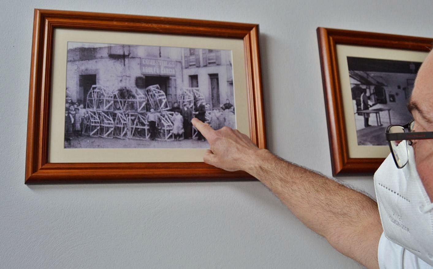 El propietario de La Luarquesa señala una foto de la tienda de ultramarinos, antesala de la panadería, que abrieron sus bisabuelos. 