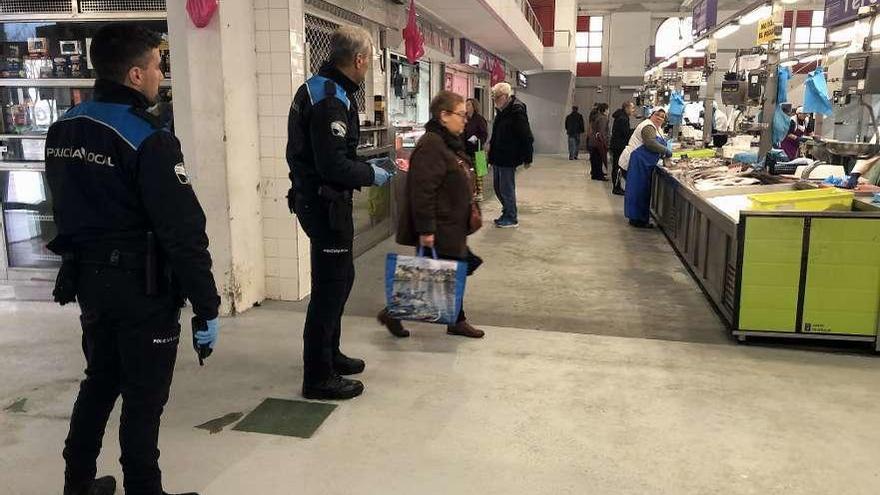 Dos agentes de la Policía Local de Cangas, supervisando las distancias de seguridad en la plaza. // G.N.