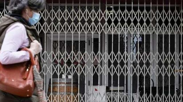 Una mujer pasa ante un bar cerrado de Gijón.
