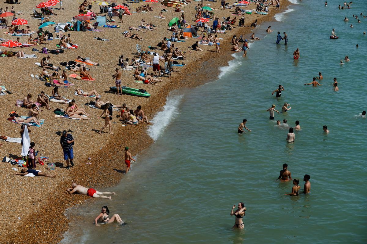 La gente disfruta del clima cálido en la playa de Brighton, durante una ola de calor en Brighton, Gran Bretaña.