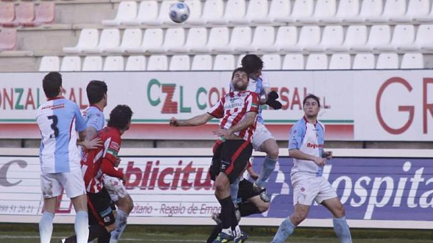 El central rojiblanco Manu Arias intenta despejar el balón ante el acoso de un delantero del Compostela.