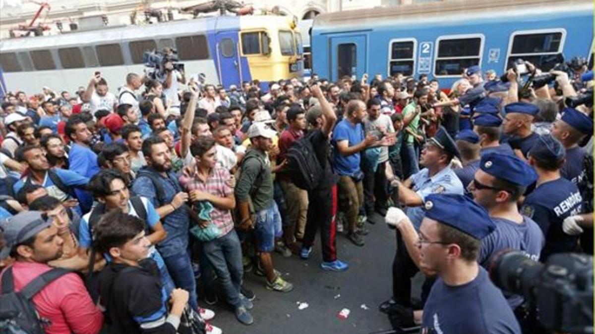 REBELIÓN Centenares de personas plantan cara a la policía hungaresa al denegársele el acceso a los trenes en dirección a Alemania, ayer.