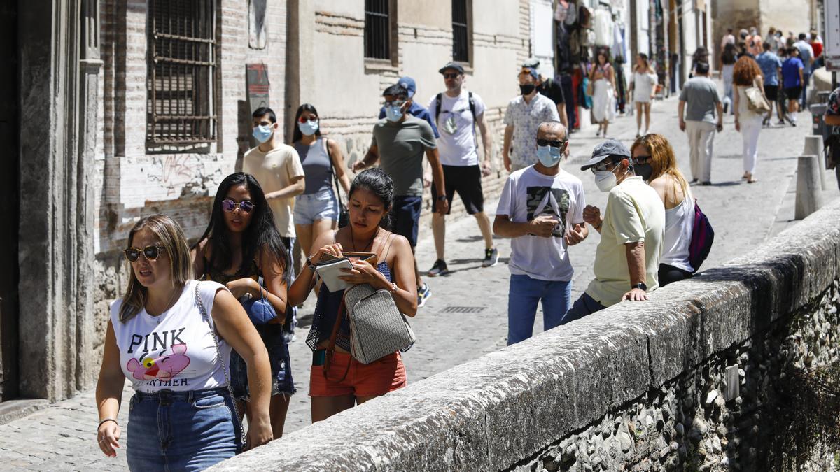 Varias personas pasean con y sin mascarilla en Granada.