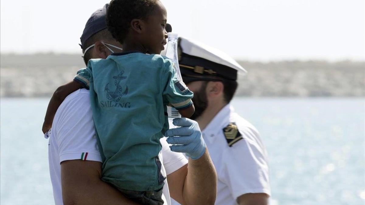 Un medico tiene en brazo un niño desembarcado del barco de la Guardia de Finanza en Pozzallo