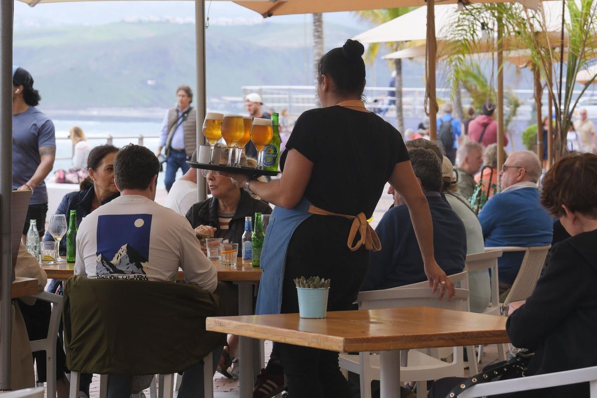 Una camarera en un restaurante del paseo de Las Canteras, en Las Palmas de Gran Canaria, atiende a un grupo de clientes.