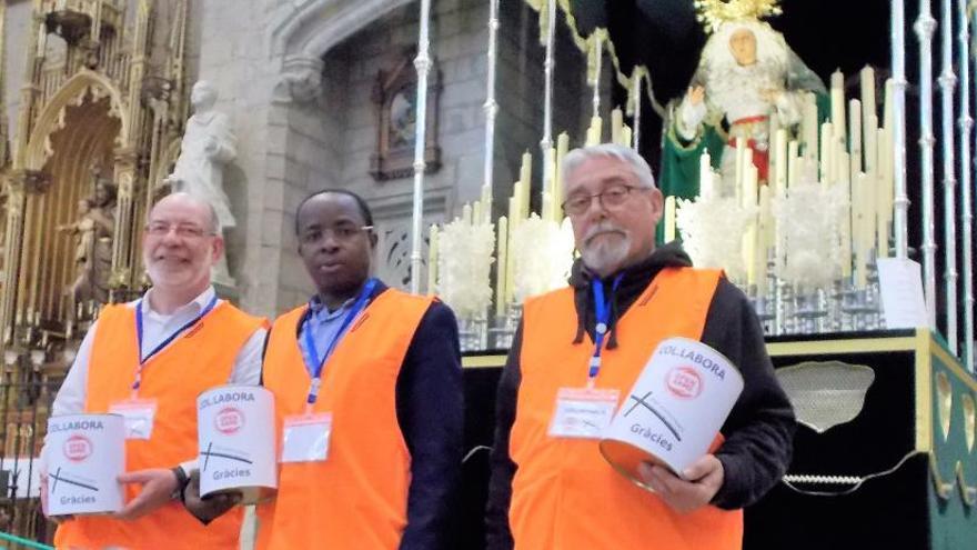 Selvas, mossèn Joan i Muñoz vestint les armilles de salvament d&#039;Open Arms i amb guardioles a les mans. Rere seu, el pas de la Macarena