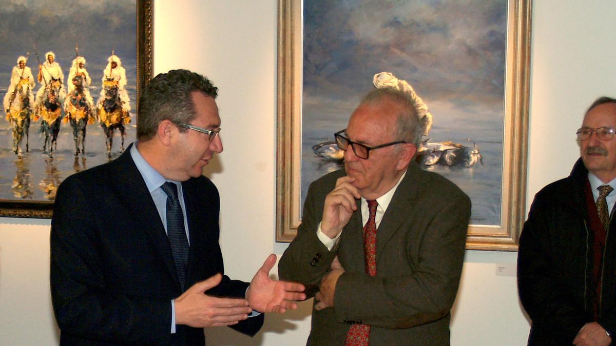 El pintor José Albero conversa con el alcalde, ante algunos de sus cuadros, en imagen de archivo.