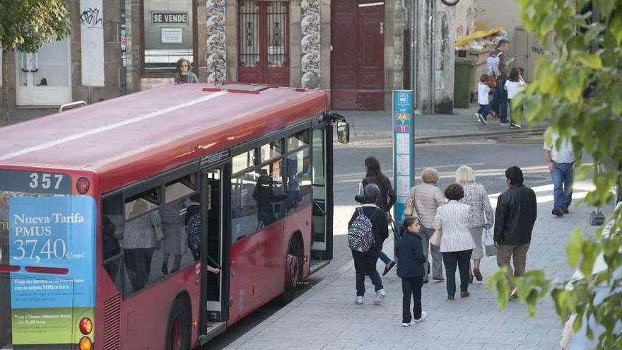 Un grupo de personas sube a un autobús en la plaza de España.