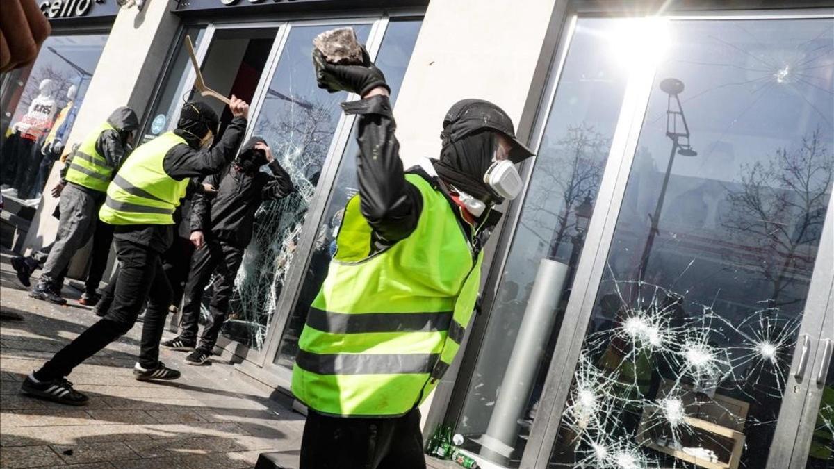 Un 'chaleco amarillo' rompe el cristal de una tienda en los Campos Elíseos de París