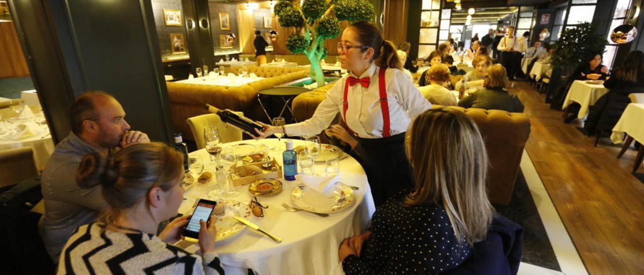 Una camarera sirve el vino a unos clientes en un restaurante de Elche.