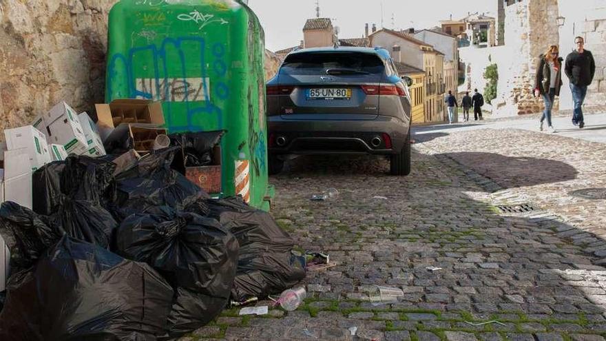 Turistas transitan por la calle Herreros, ayer, con la basura del día anterior sin recoger.