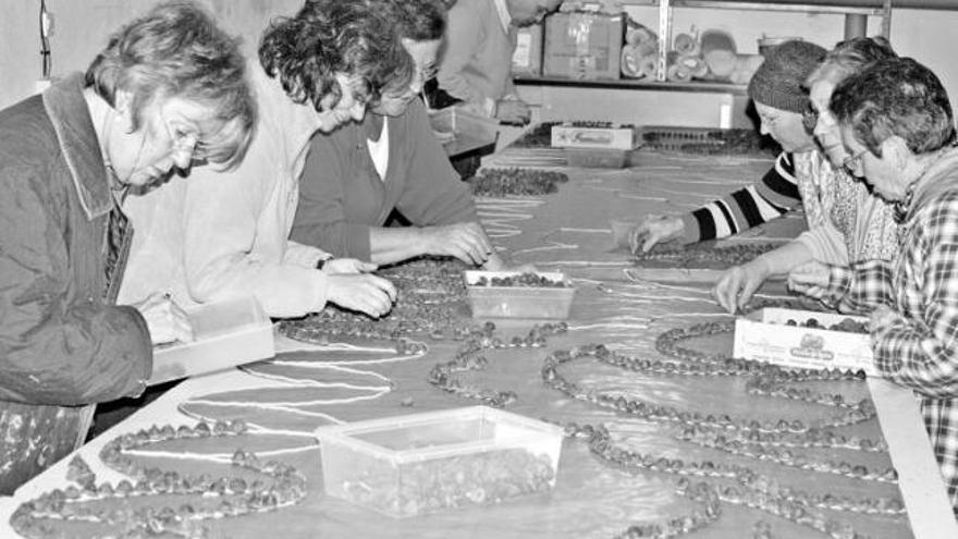 Un grupo de vecinos, trabajando a pleno rendimiento sobre la plantilla en un garaje de la villa castropolense.