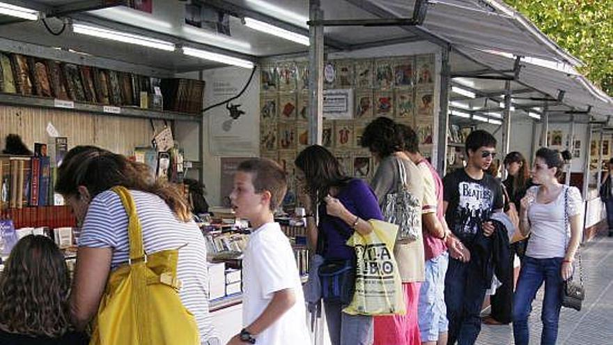 Varias personas miran los libros expuestos en la feria.