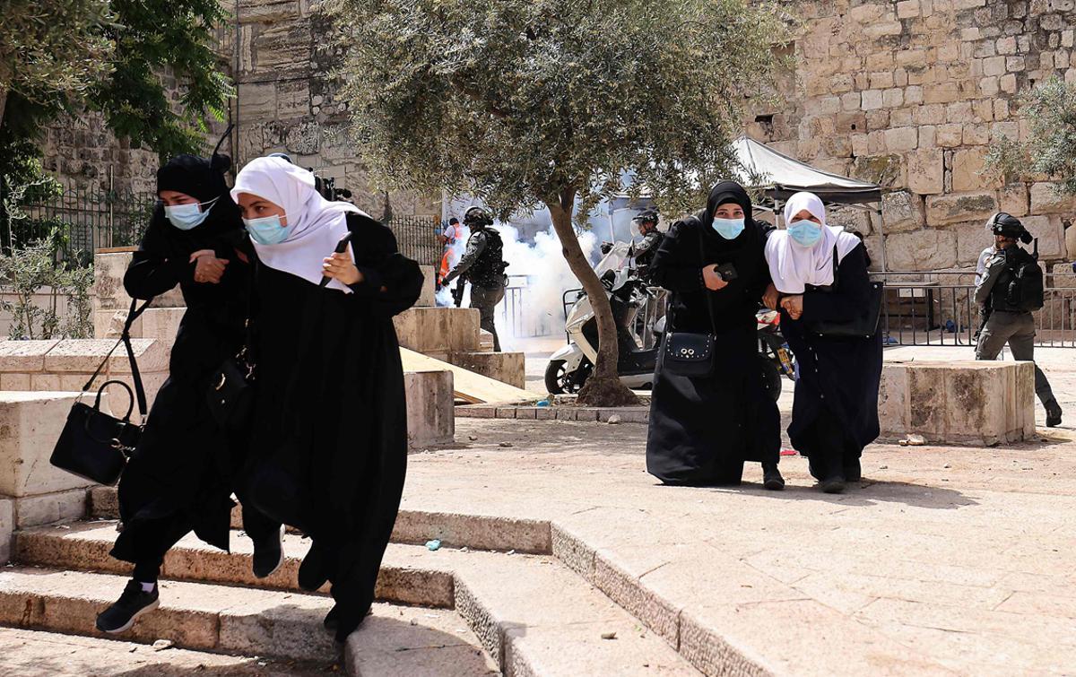 Palestinos corren para refugiarse de los gases lacrimógenos lanzados por las fuerzas de seguridad israelíes en la Ciudad Vieja de Jerusalén.