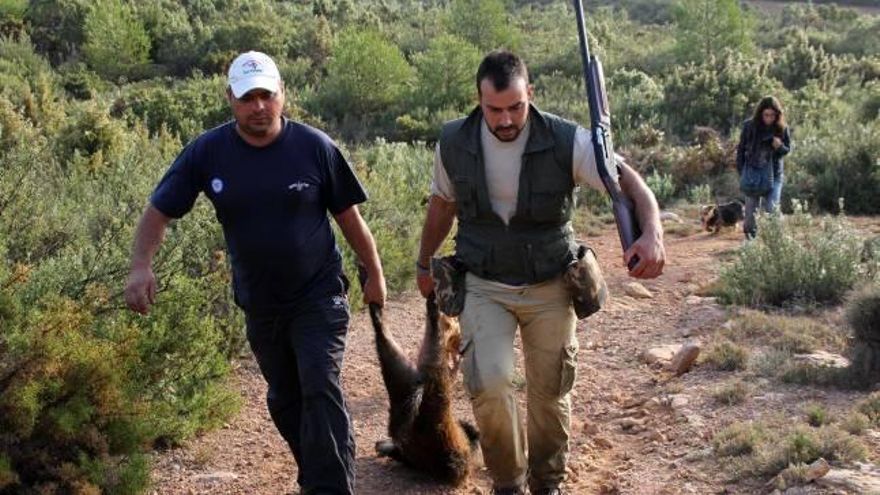 Dos cazadores arrastran una pieza abatida.