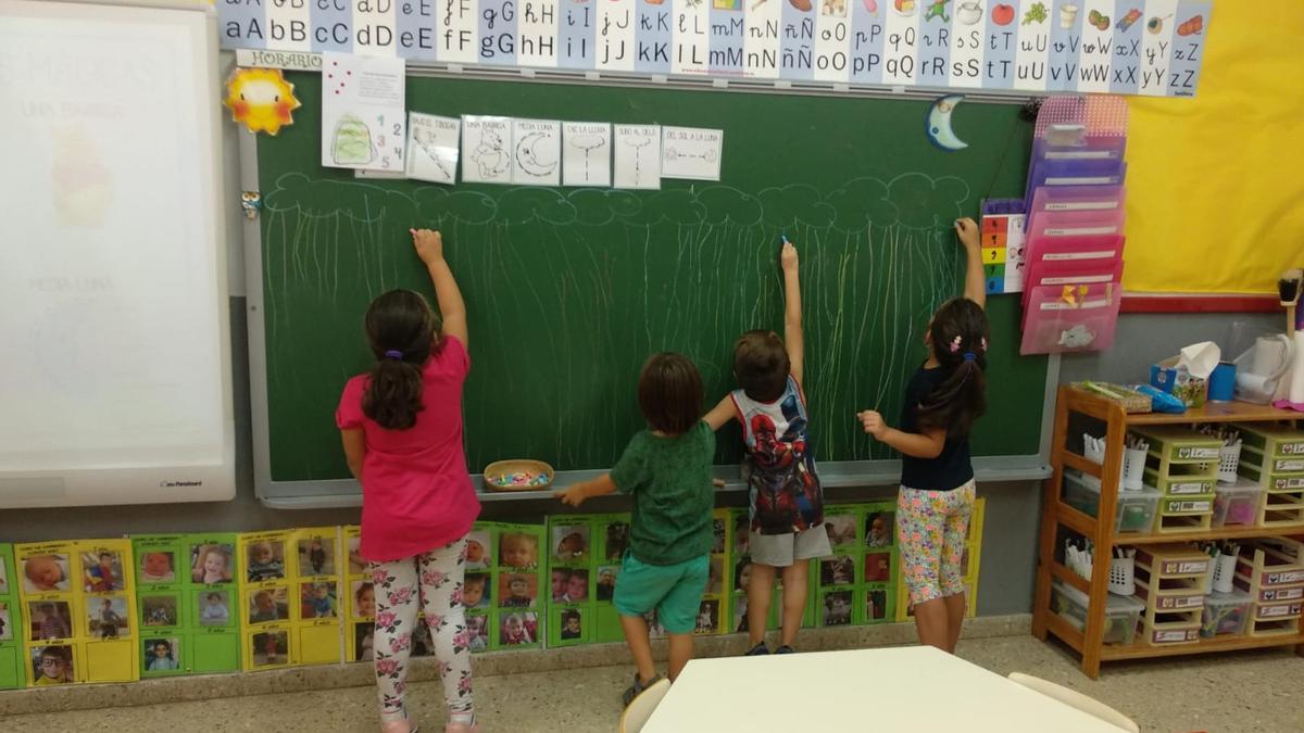 Escolares dibujan en la pizarra de su aula.
